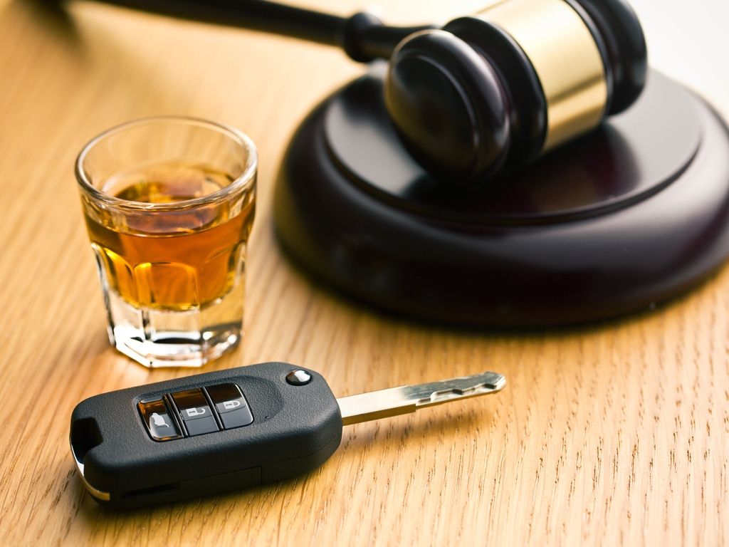 car keys, a glass of whiskey and a judge’s hammer on the table